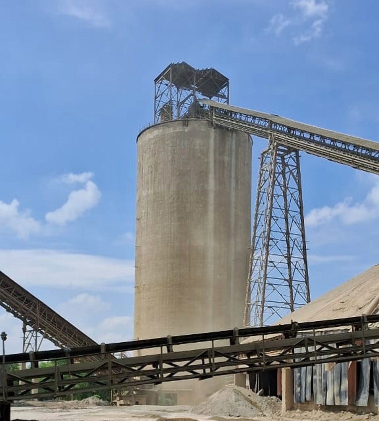 A cement silo with conveyor galleries and material stockpiles at an operating plant